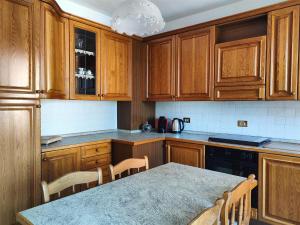 a kitchen with wooden cabinets and a table with chairs at IseoLakeRental - Casa Chicca in Esmate