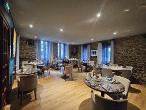 a restaurant with tables and chairs and a stone wall at Logis Hôtel-restaurant Le Grand Cerf in Ernée