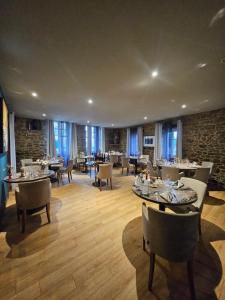 a dining room with tables and chairs and windows at Logis Hôtel-restaurant Le Grand Cerf in Ernée