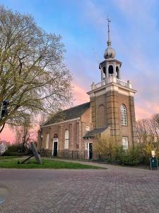 a church with a tower with a cross on top of it at Urker Ussien in Urk