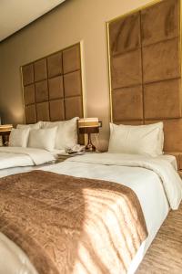 2 Betten in einem Hotelzimmer mit weißer Bettwäsche in der Unterkunft Grand Sapphire Hotel in Almaty
