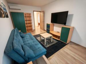 a living room with a blue couch and a tv at Sandline in Kecskemét