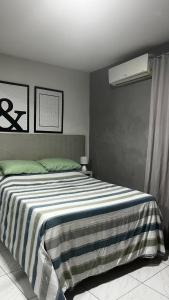 a bedroom with a large bed with a striped blanket at Apt FIG 2025 in Garanhuns