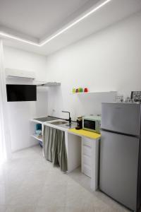 a white kitchen with a refrigerator and a sink at Dream on the blue house 2 in Valderice