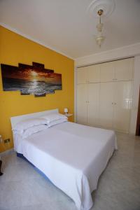a bedroom with a white bed and a yellow wall at Dream on the blue house 2 in Valderice