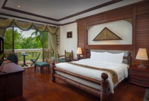 a bedroom with a bed and a large window at Borei Angkor Resort & Spa in Siem Reap
