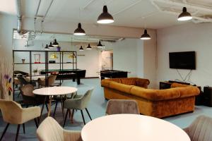 un salon avec un canapé, des tables et des chaises dans l'établissement YouthMents - Student Hotel, à Riga