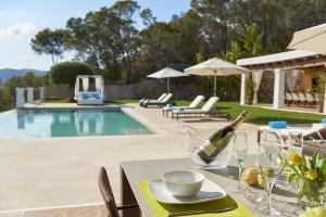 einen Tisch mit einer Flasche Wein neben einem Pool in der Unterkunft Luxury Ibiza Villa with Stunning Views, 1311 in Sant Carles de Peralta