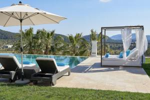 eine Terrasse mit 2 Stühlen und einem Sonnenschirm neben einem Pool in der Unterkunft Luxury Ibiza Villa with Stunning Views, 1311 in Sant Carles de Peralta