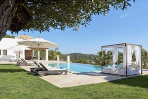 einen Pool mit 2 Liegestühlen und einem Sonnenschirm in der Unterkunft Luxury Ibiza Villa with Stunning Views, 1311 in Sant Carles de Peralta