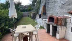 Una mesa y sillas y una sombrilla junto a un horno de ladrillos. en Argentina home VERRANDI, en Trucco