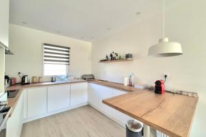 a kitchen with white cabinets and a wooden counter top at Superb house with garden - Saint-Coulomb in Saint-Coulomb