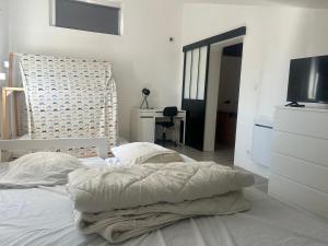 a white bedroom with a bed and a desk at Maison a étages bord de mer in Notre-Dame-de-Monts