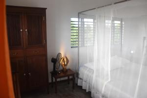 a bedroom with a bed with white curtains and a table at villa Erica bella vista in Hell-Ville +52 photos