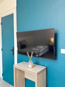 TV de pantalla plana colgada en una pared azul en Appartement Platanes 7 - Proche Disneyland - Parking Gratuit - Meaux, en Meaux