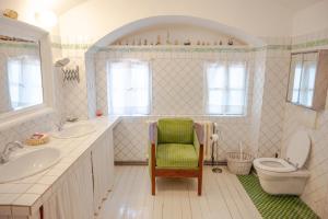 a bathroom with a sink and a toilet and a chair at Family Hotel Okoř in Okoř +83 photos