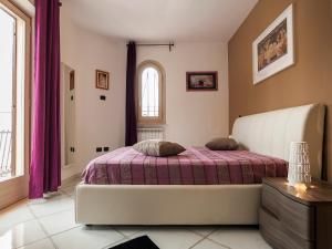 sypialnia z łóżkiem z fioletową pościelą i oknem w obiekcie Villa Omero w mieście Sperlonga