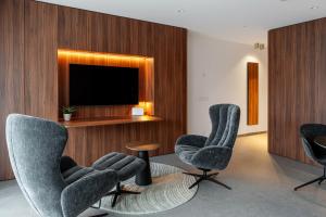 a living room with three chairs and a television at Core Luxembourg -Studio Parking -50 Cents in Luxembourg
