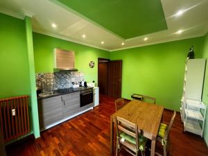 a kitchen with green walls and a wooden table at Grado by ACS HOLIDAYS in Lido di Ostia