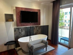 a bathroom with a tub and a tv on the wall at Grado by ACS HOLIDAYS in Lido di Ostia