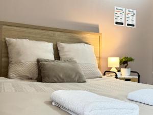 un letto con cuscini bianchi e testiera in legno di Studio Platanes 3 - Proche Disneyland - Parking gratuit - Meaux a Meaux