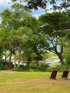 two chairs sitting in the grass near a river at Gaia Lake Bungalow Kandalama in Dambulla