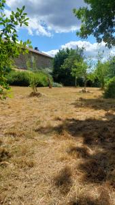 a field of grass with trees and a building at Chambres indépendantes dans maison à la campagne in Le Monteil-au-Vicomte