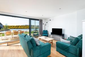 a living room with two blue couches and a television at The Lark Ascending BR11 Silverlake Dorset in Warmwell