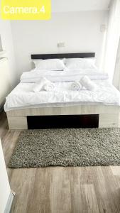 un letto con lenzuola bianche e un tappeto in una camera da letto di Vila Eric LG a Budeşti