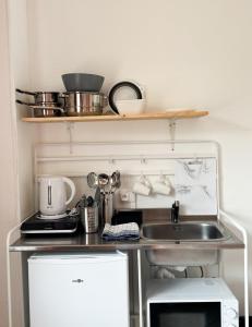 una pequeña cocina con fregadero y estante en Studio Platanes 4 - Proche Disneyland - Parking gratuit - Meaux, en Meaux
