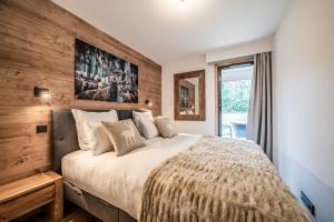 una camera da letto con un letto grande con una parete in legno di Apartment Alpinea, Les Houches - by EMERALD STAY a Les Houches