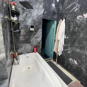 a bath tub in a bathroom with a green door at Yuqori Uy Mexmonxonasi in Kokand