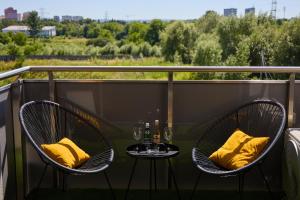 ジェシュフにあるApartament Niebieski Horyzont Kopisto 11 Centrum Miasta Rzeszówのバルコニー(椅子2脚、テーブル、黄色い枕付)