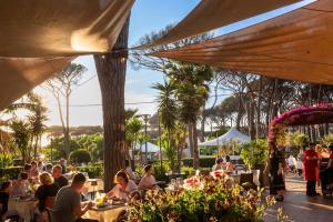a group of people sitting at tables in a restaurant at Fabulous village in Casal Palocco