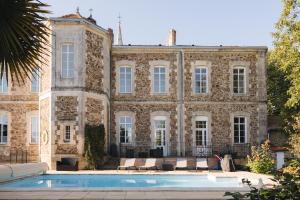 a large stone building with a swimming pool in front of it at Le Cocon Spa proche Puy DuFou in Mesnard-la-Barotière