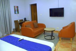 a hotel room with a bed and a chair and a tv at Caritas Inn, Ilasan in Lagos