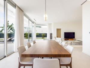 a dining room with a wooden table and white chairs at High Luxury Villa Martina, ABAMA in Tejina de Isora
