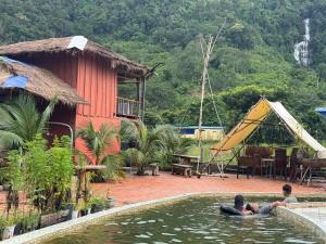 two people swimming in a pool of water in front of a house at Chamka Sne LyLy Resort in Phumĭ Stœ̆ng Chral