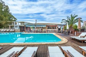 una piscina con tumbonas y mesas en una terraza de madera en Nereides Hotel, en Chaniotis