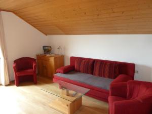 a living room with a red couch and two chairs at Ferienwohnung Panorama in Bad Kohlgrub