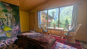 a bedroom with a table and chairs and a painting at Alpine Homes by Kayal Wood in Kulu