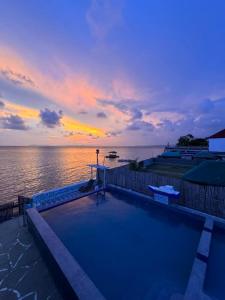 a swimming pool next to the ocean with a sunset at La Evangs Beach Resort Taal in San Luis
