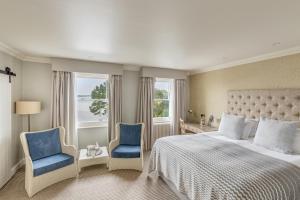 a bedroom with a bed and two blue chairs at Harbour Hotel & Spa Christchurch in Christchurch