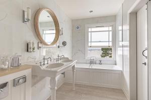 a bathroom with two sinks and a tub and a mirror at Harbour Hotel & Spa Christchurch in Christchurch