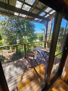 Un porche cubierto con una mesa y un banco en una terraza. en Bellingen - Hilltop Garden Studio, en Bellingen 2 fotos más
