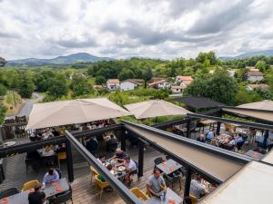 a restaurant with people sitting at tables and umbrellas at Hôtel Restaurant Aldaburua in Larressore