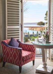 a living room with a red chair and a table at Harbour Hotel & Spa Christchurch in Christchurch