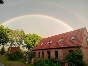 a rainbow in the sky over a brick building at Der Eulenblick - Seminarhaus, Ferienhaus, Gästehaus, Reitstation, Am Waldrand in Tewswoos +3 photos