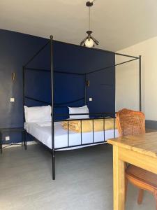 圣路易斯HÔTEL ETOILE DU SUD的一间卧室配有一张黑色天蓬床和一张桌子 更多10张照片