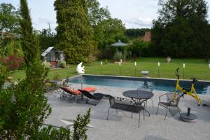 a patio with a table and chairs next to a pool at Au temps suspendu in Champagney